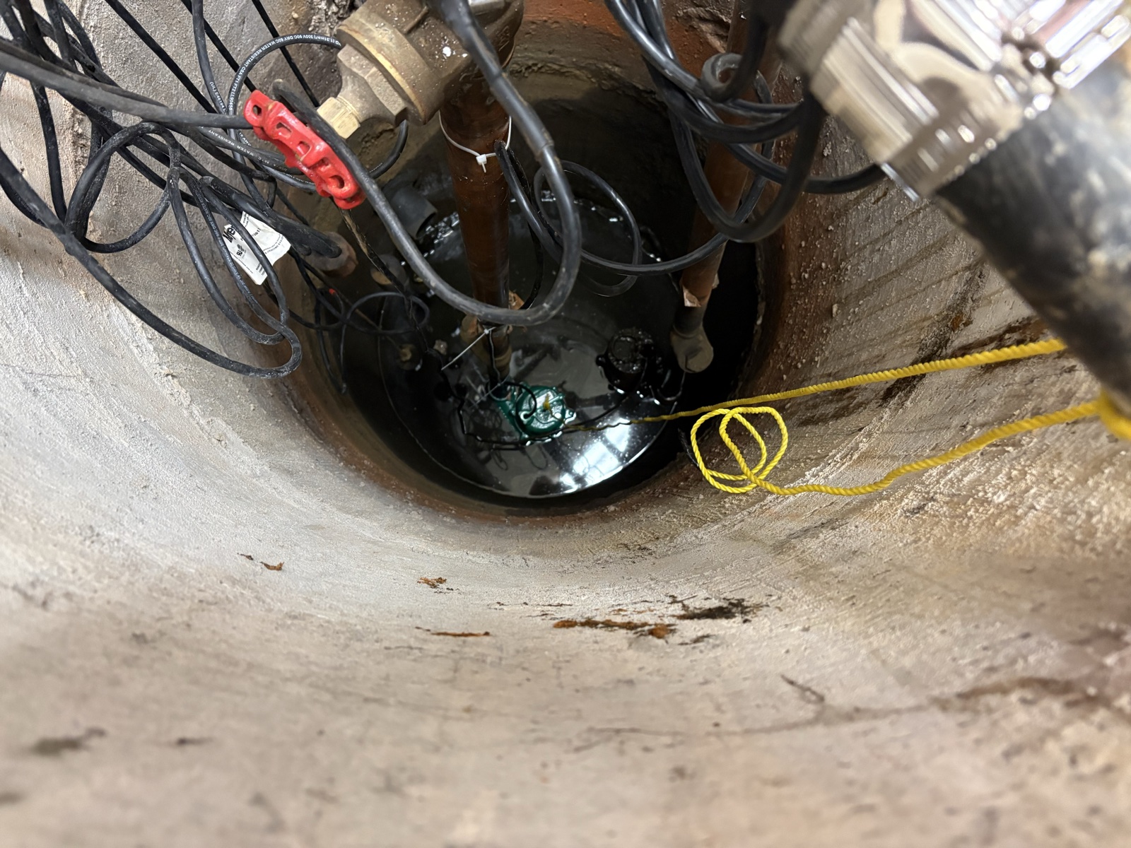 Real Thomas Plumbing job. Close-up of a North Bay basement sump pit with submersible pump and discharge piping serviced by Tyler Thomas.