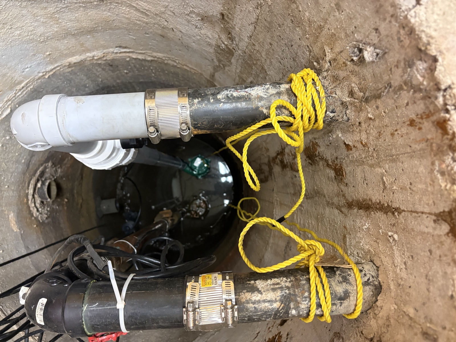 Real Thomas Plumbing job. North Bay sump pit with primary submersible pump and rope-attached battery-backup pump installed by Tyler Thomas.